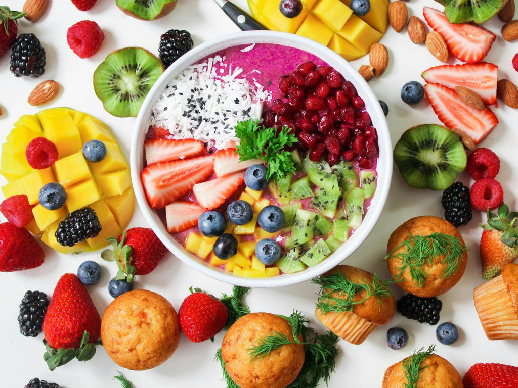 An acai bowl full of colourful fruit, surrounded by mangos, strawberries and kiwi